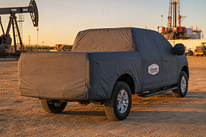 Covered pickup — make and cabin out of sight on an outdoor lot.